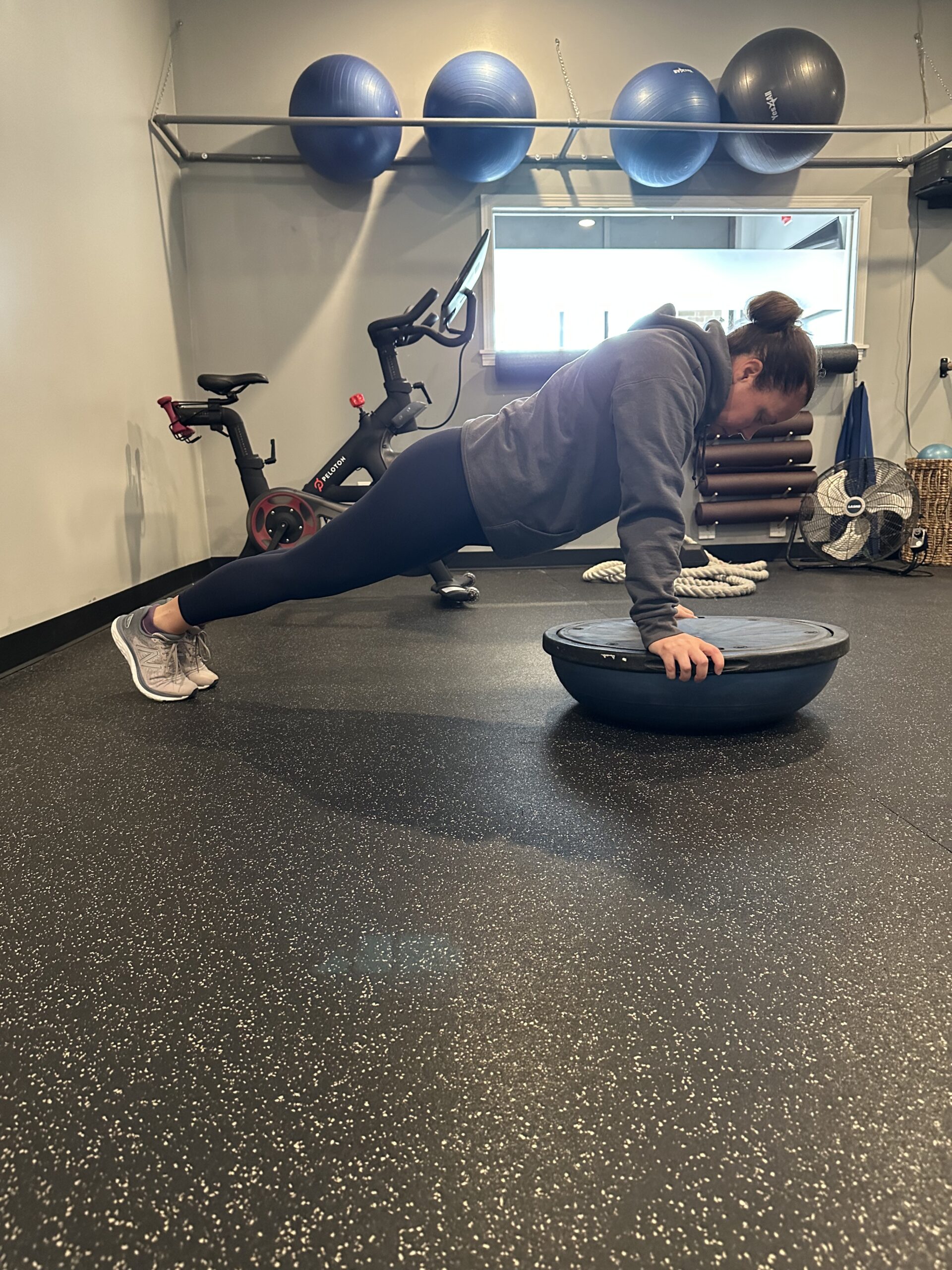 Female personal trainer doing a plank on a bosu ball.