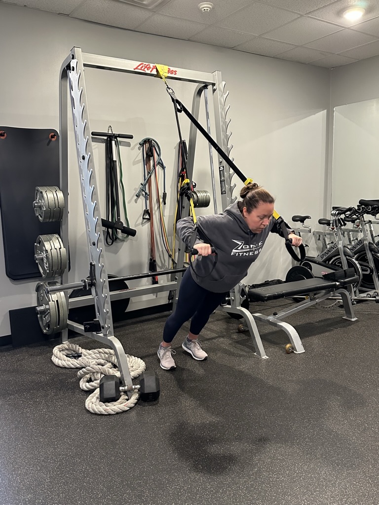 Female personal trainer doing chest presses on an exercise rack